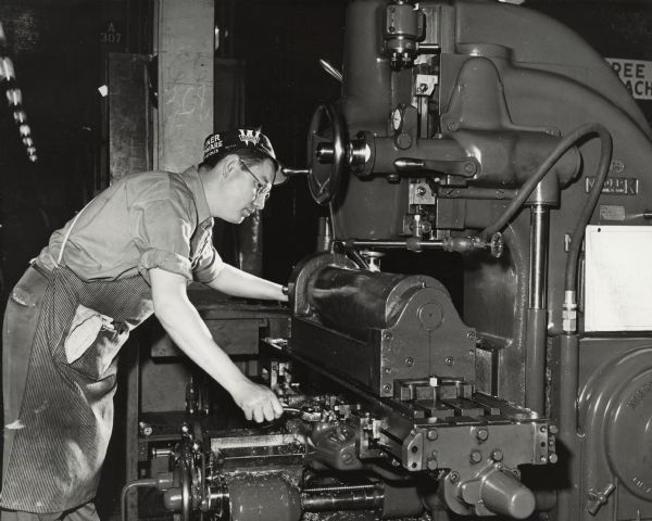 Factory worker at IH 20mm gun plant. Original caption states: "Nearly all of the men employees of the plant also were trained by the company in special training classes for the war production jobs. Here, Millen S. Whittington, a former motor truck salesman for the International Harvester Company who transferred from sales to war production after the company ceased the manufacture of civilian motor trucks, is shown operating a machine at Harvester's gun plant."