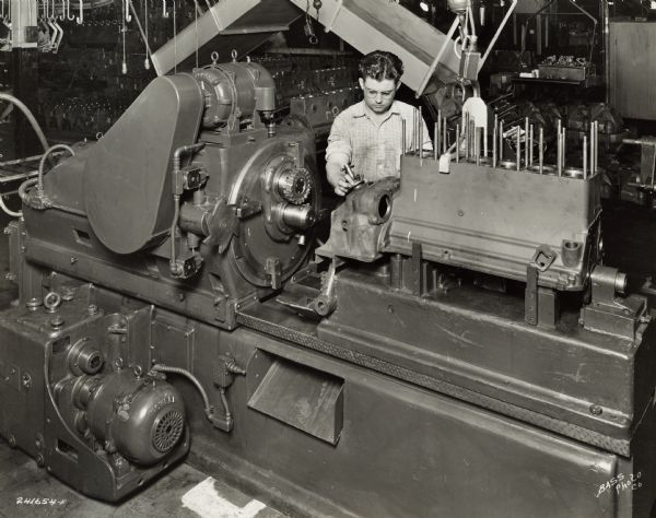 Factory worker at International Harvester's Indianapolis Works.  Original caption states: "M.F. and John Barnes machine with planetary milling head for finish facing and boring transmission face of flywheel housing after assembly to cylinder block, which assures perfect alignment of transmission to engine assembly."