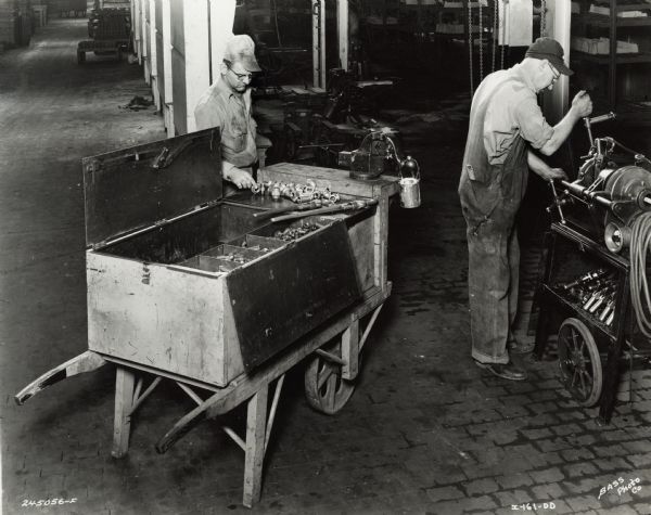 Factory workers at International Harvester's Indianapolis Works (Truck Engine Works). Original caption states: "One of the foundry maintenance operations, showing a pipe crew using a portable pipe threading machine and a combined portable tool box and work table."