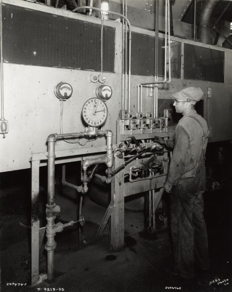Factory worker at International Harvester's Indianapolis Works (Truck Engine Works). Original caption states: "Plug in type ammeters prove to be better protection than overload relays on sand mullers. The operator may watch his motor load during the operation and thus keep within rating of motor."