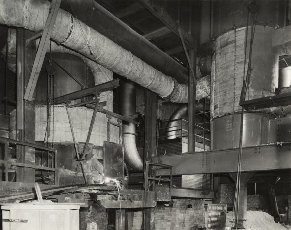 Factory worker at International Harvester's Indianapolis Works (Truck Engine Works). Original caption states: "Cold and hot air piping between cupola (on the left) and preheater (on the right).  Built by Whiting Corporation."