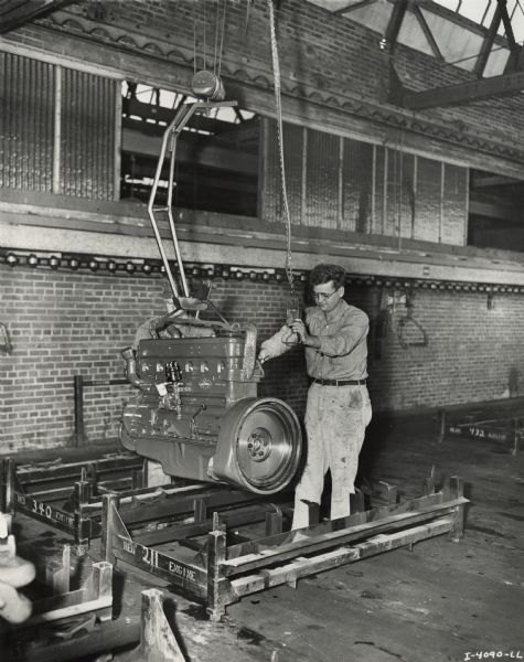 Factory workers loading a Red Diamond engine with an overhead pulley and crane system at International Harvester's Indianapolis Works.