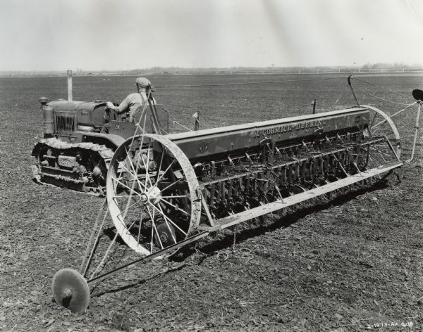 Farmer or farm worker pulls a grain drill with an International T-20 TracTracTor (crawler tractor). The tractor was owned by the Campbell Brothers.