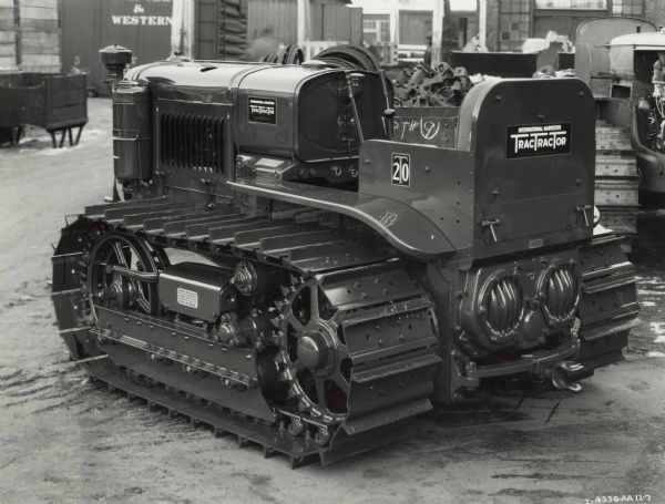 International T-20 TracTracTor (crawler tractor) sitting in a yard with railroad cars and machine pieces in the background.