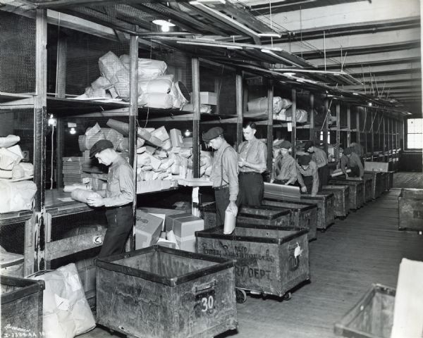 Men loading small packages into rolling carts in the shipping department of Emery Bird Thayer Dry Goods Co.
