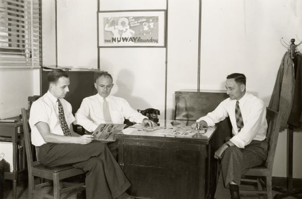 Three officials of the Nuway Laundry examine International truck cost records. The original caption reads: "Officials of The Nuway Laundry of Long Beach, Calif., owner of a fleet of Model D-2 panel trucks. (See photos in the No.193 series), examining International Truck Cost Records, which are kept on all trucks operated. Reading from left to right: Robert M. Place, secretary; Earle G. Place, president, and L.C. Thompson, general manager."