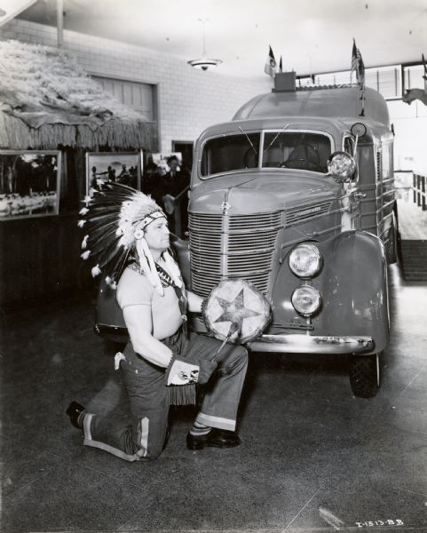 "Chief Lone West", Cherokee movie actor from Santa Monica, poses in a headdress near an International truck. According to the original caption, he was also a football player (or possibly rugby?) on the 1920 United States Olympic team.