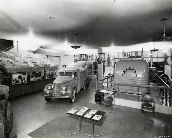International Harvester showroom (possibly part of a dealership or branch house) in Manhattan. The showroom features an exhibit on an Attilio Gatti expedition to Africa. The exhibit includes International trucks designed specifically for the expedition. One of the truck was referred to in company advertising as a "jungle yacht." The original caption reads: "Interior of Manhattan International showroom with de luxe trailers streamlined with International truck-tractors. Showing elevated platform around the trailers during exhibit April 1938, when eight to ten thousand people viewed the display. Jungle setting in background."