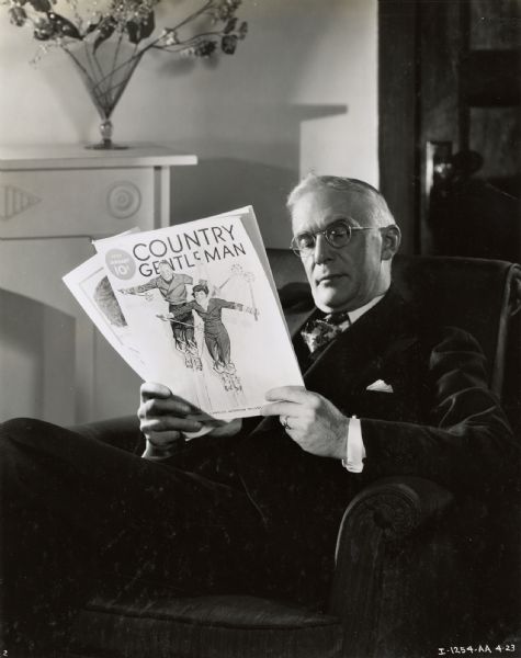 A man sits in an armchair reading the magazine "Country Gentleman."