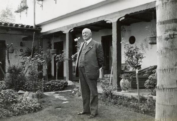 C.H. Haney, former manager of foreign sales, stands outdoors in front of the porch of his home.