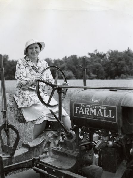 Mrs. Frank Bohn sits behind the wheel of a Farmall F-20 tractor.