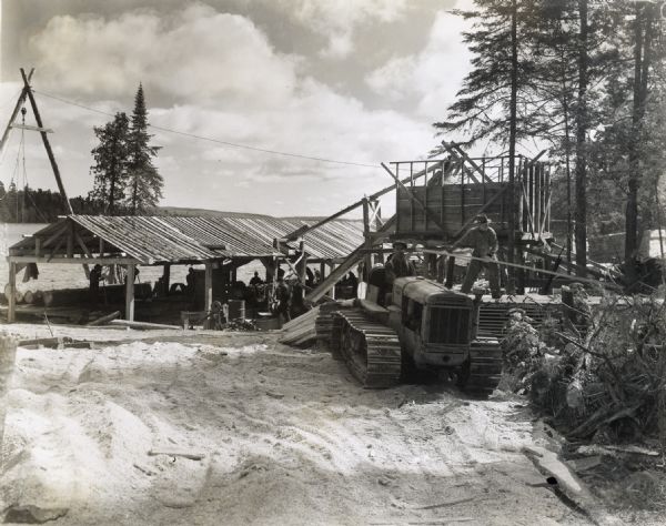 Men using an International T-20 TracTracTor (crawler tractor), PD-80, and P-300 owned by Sam Seppala of Grand Marais, to log white pine. The original caption reads: "Logging and sawmill 5 miles west of Grand Marais. Producing an average of 16,000 feet of white pine per day.  Using 30 to 35 gallons of Diesel fuel on PD-80 on sawmill in 8 hours.  Has produced 17,400 feet in 8 hours. T-20 using 1 1/2 gallons per hour. Very happy over his purchase."