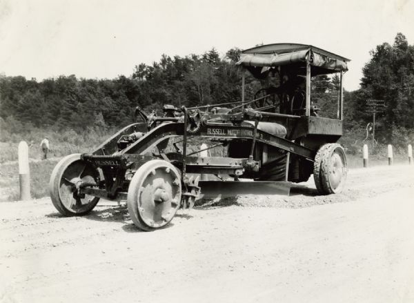 Emil Anderson operating a road grader marked "Russell Motor Patrol No.3" on Highway 12.