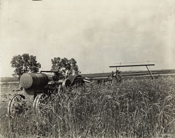 A man pulls a grain binder through a field of grain with a Titan 10-20(?) tractor.