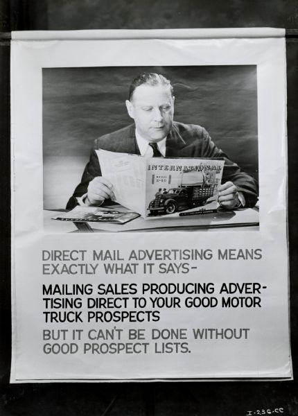 A man looks at an International D-40 Truck advertisement in a banner for the Canadian motor truck advertising program. The original caption reads, "Canadian motor truck advertising program - charts used at Calgary and Montreal M.T. sales conference."