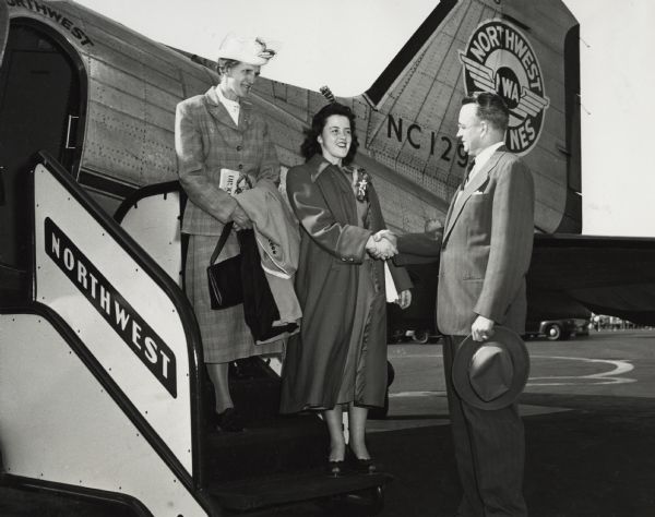 Original caption states:  "Alpha Bungum, 17, of Kasson, Minn., receives congratulations from A.S. Knudsen, northwest regional manager, general line sales, International Harvester, as she and her chaperone, Mrs. Edd Holtan, left, 4-H leader from Byron, Minn., arrive at Chicago Municipal Airport on a Northwest Airlines plane.  Miss Bungum's and Mrs. Holtan's week-end trip to Chicago was sponsored by the Allen-Lloyd Co., IH dealer at Rochester.  Miss Bungum was crowned queen of the 12th annual Gypsy Festival in Rochester on Saturday, April 30."