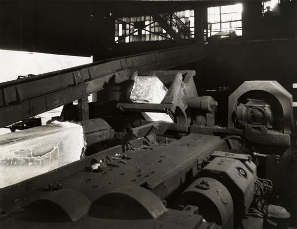 Blooming mill at International Harvester's Wisconsin Steel Works. Original caption reads in part: "New Blooming Mill, Wisconsin Steel Works. Photo No. 2 -- Discharching ingot on to mill approach table rolls, with another ingot in foreground already on its way to the 40" blooming mill."