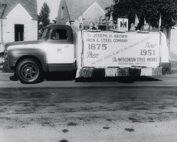 Side view of a Joseph H. Brown Iron & Steel Company International Harvester truck decorated with flags and banners for Chicago's East Side Centennial Parade. The text on the banner reads, "The Joseph H. Brown Iron & Steel Company; The First Steel Plant in the Calumet District; The Wisconsin Steel Works, International Harvester Co.; 1875 Then - Now 1951."