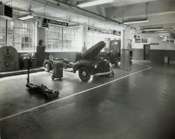 An International truck axle and engine sit on display in what appears to be a dealership showroom. A truck body is in the background. This may be part of International Harvester's education and training center.