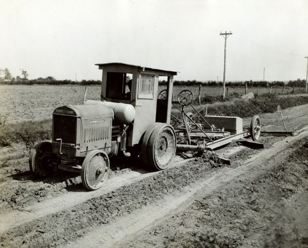 A Nebraska State Highway Department worker uses a McCormick-Deering 10-20 industrial tractor with an Adams maintainer to work on a rural road.