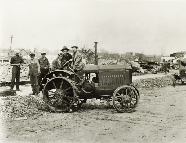 A group of men gathering around a McCormick-Deering relief tractor in an area damaged by the "tri-state tornado." The tractor may be an 10-20.