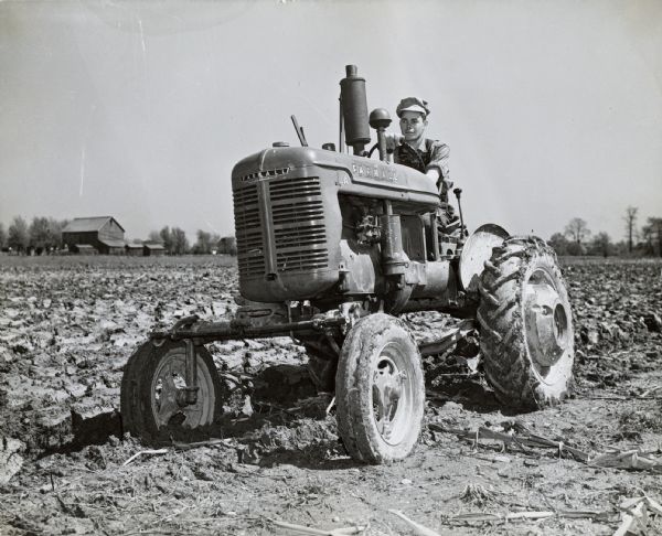 Robert Frase, a tenant on the A.L. Roads farm, sits on a Farmall A tractor equipped with Goodyear synthetic tires and an A-192 one-furrow Farmall plow.