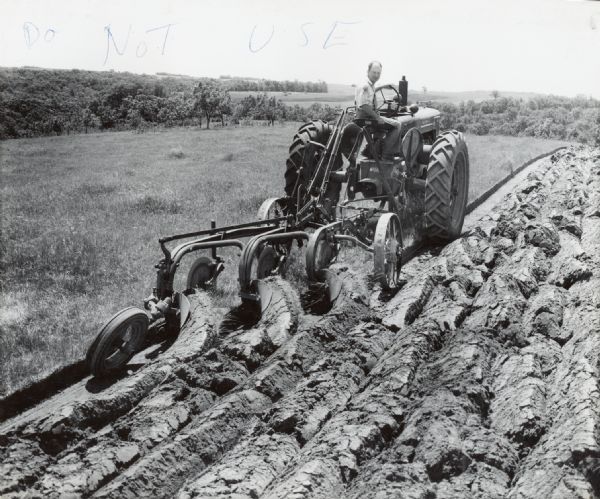 G.F. Klassy operates a McCormick-Deering Farmall M with a Number 15 Genius tractor plow on his farm on Route 1.