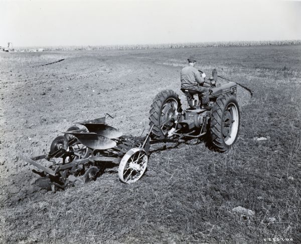 Elevated view of a man using a McCormick-Deering Farmall H with a Number 39 two-way roll-over plow to build a terrace.