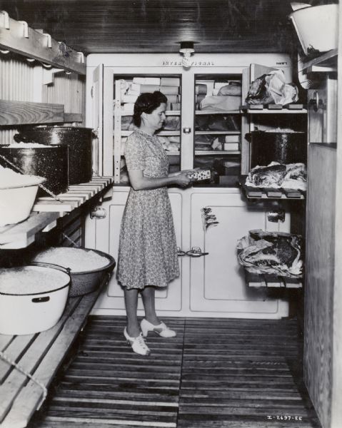 Mrs. Wilbur Shrieder stands in a 6 x 12 foot refrigerated walk-in storage area.