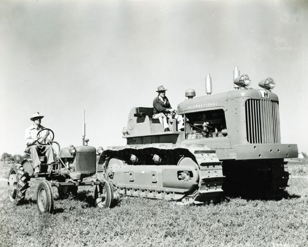 Two men are demonstrating a Farmall Cub tractor and an International diesel TD-24 in a field on International Harvester's Hinsdale experimental farm.