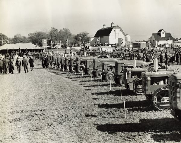Men examiinge farm equipment, farm tractors and crawler tractors (TracTracTor) on display at International Harvester's Hinsdale experimental farm.