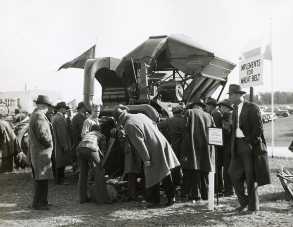 A group of men gather around a cotton picker on display at International Harvester's Hinsdale experimental farm.