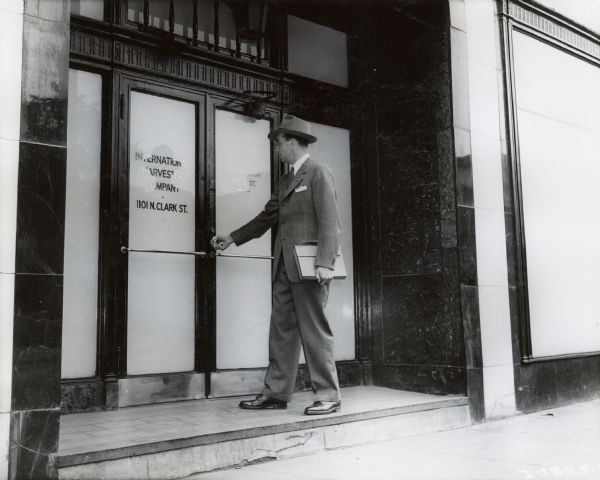 A man wearing a suit and hat approaches the entrance to International Harvester's Education and Training Center.