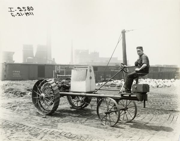Man sitting on an experimental lightweight tractor. The photograph was probably taken outside International Harvester's McCormick Works. Original caption includes the name "John F. Steward".