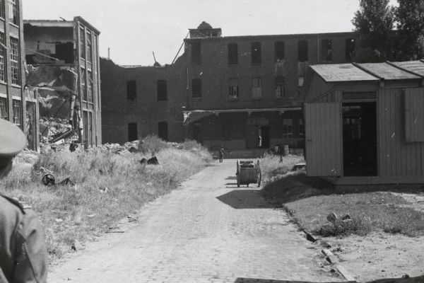 Man standing and looking at buildings, possibly war-damaged, at International Harvester's Neuss Works in Germany. The Binder Twine Mill is located on the left.