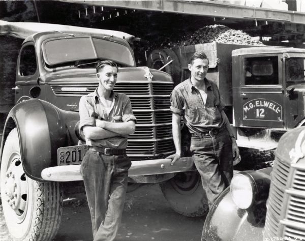 Roy Liddard and Harold Murphy, employees of hauling contractor M.G. Elwell, stand with several International trucks.