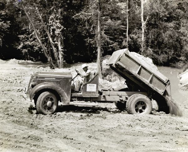 A man uses an International dump truck to unload dirt in a wooded area between Natchez, Mississippi, and Nashville, Tennessee.