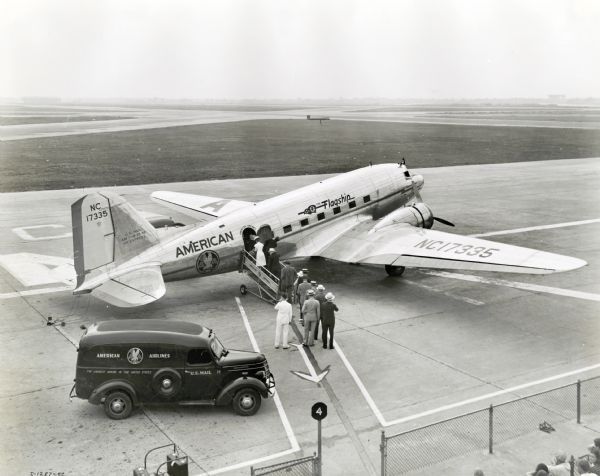 Elevated view of group of men and women boarding an American Airlines airplane while an International D-15 truck marked "U.S. Mail" and "American Airlines" is parked in the foreground.