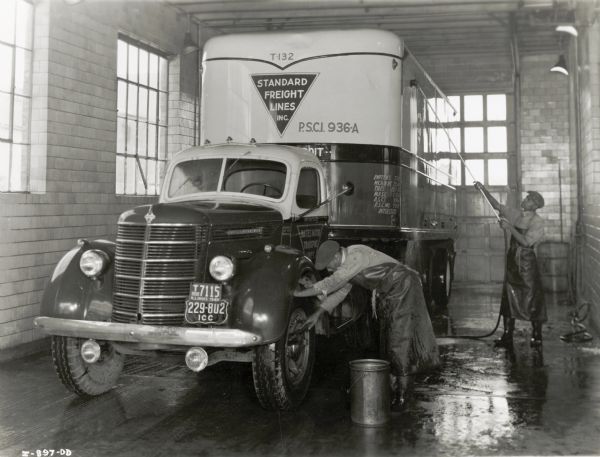 Men in a washroom are cleaning an International truck used by Standard Freight Lines, Inc. The original caption reads: "Truck washroom. American Transportation Company, Chicago."