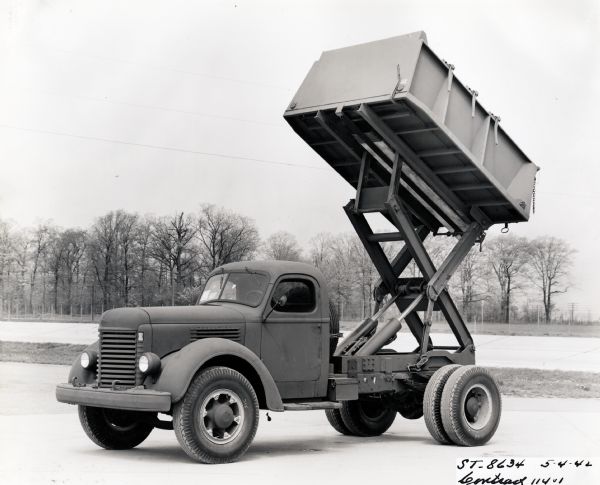 Side view of an International KR-11 dump truck with the bed raised. The original caption reads: "KR-11 M.T. Government Model, Contract 11401."