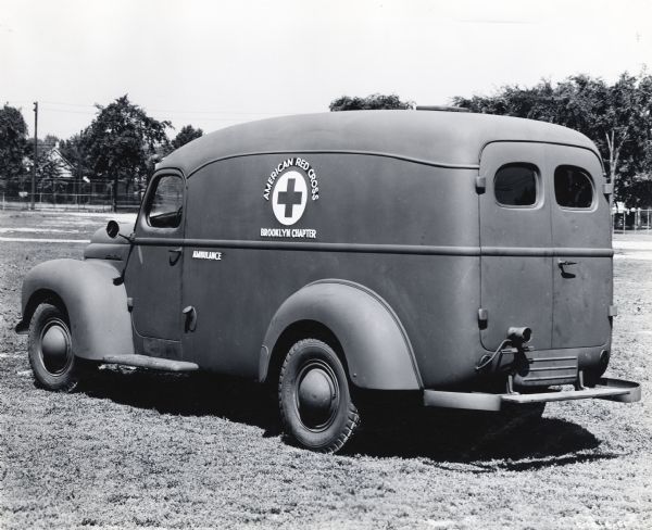 An International truck used as an ambulance by the American Red Cross Brooklyn Chapter parked in a field.