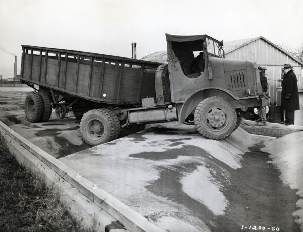 Men look on as a man drives an International truck on a test track. The truck may be a model designed for the U.S. military. The photograph may have been taken at International Harvester's Fort Wayne Proving Grounds.