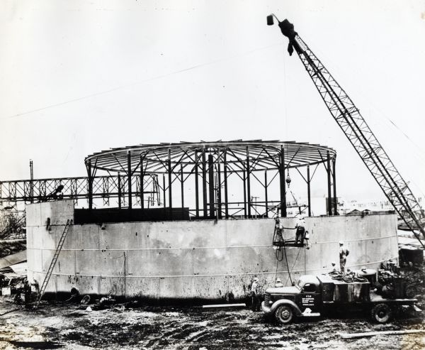 The 56th Construction Battalion of Seabees dismantles fuel tanks using a crane and an International K-line truck. The original caption reads: "Project No. 56-PH."
