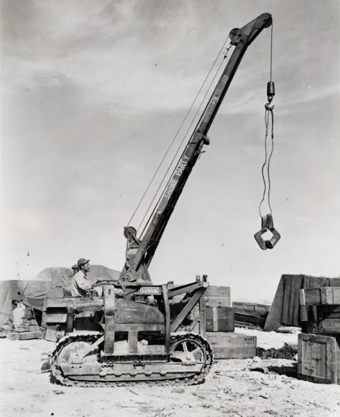 Seabees use an International crawler tractor (TracTracTor) with a crane ("cherry picker") to load cargo on a Western Pacific island. The text on the crane reads: "Shore Party."