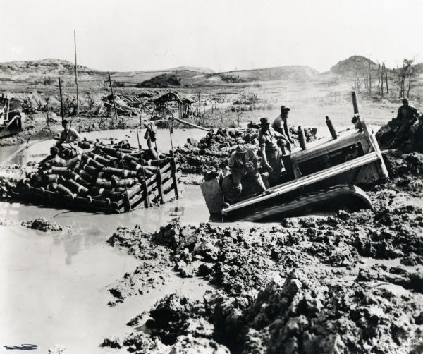 Marines use an International TD-18 Diesel crawler tractor (TracTracTor) to pull an ammunition trailer from the mud. The original caption reads: "JAPANESE ALLY--The island is tactically 'secured' but rivers of mud conspire with die-hard Jap [sic] individuals to make mopping up a rugged business on Okinawa. It is taking an International TD-18 Diesel crawler tractor to pull this ammunition trailer out of the waist-deep mire."