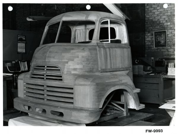 Full-size model of an International truck cab made out of wood. The model sits on a platform inside a garage or studio space, and was likely made by an industrial designer.