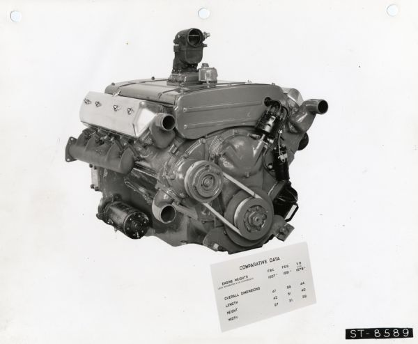 Side view of an International engine against a white background. There is a sheet listing comparative engine statistics in the foreground.