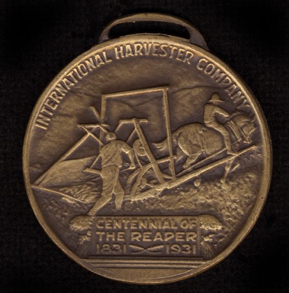 Back side of a coin made for International Harvester to celebrate the "Reaper Centennial." The event commemorated the one hundred year anniversary of the testing of the first reaper by Cyrus Hall McCormick. The illustration on the coin represents the first reaper test and is based on a painting by N.C. Wyeth.