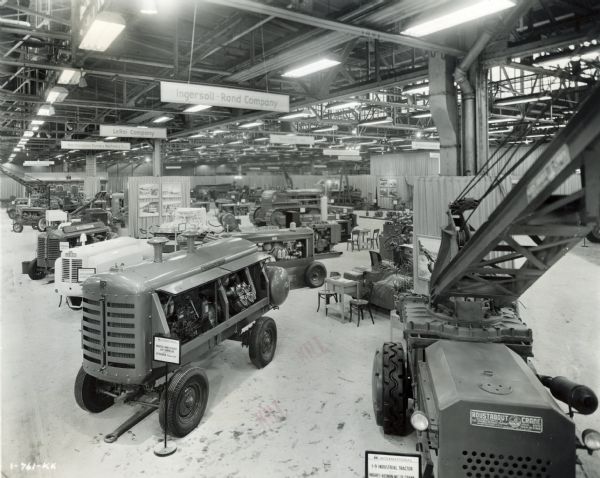 Equipment on display in the Industrial Power Exhibit for Allied Equipment Manufacturers at International Harvester's Melrose Park Works. The foreground features an Ingersoll-Rand IK-315 CU. FT. air compressor powered by a UD-18 A Diesel power unit (left) and an I-9 industrial tractor with a Hughes-Keenan MC2R crane.