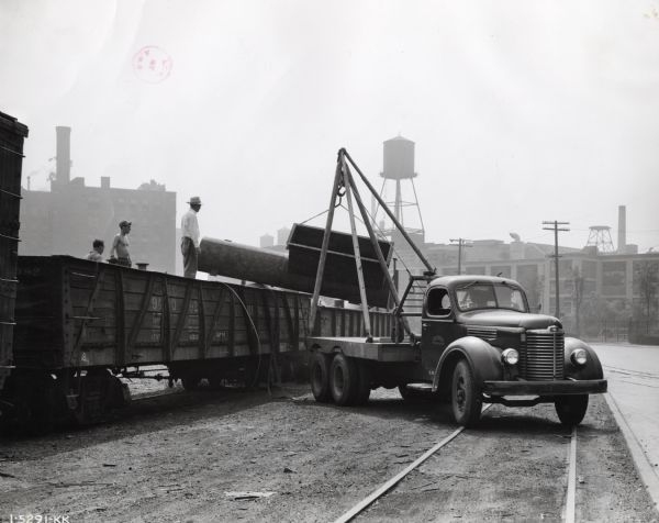 Men from the Girdler Corporation use an International KB-6 truck with a 21-foot wheelbase and a Tulsa winch to load equipment pieces into a train car.